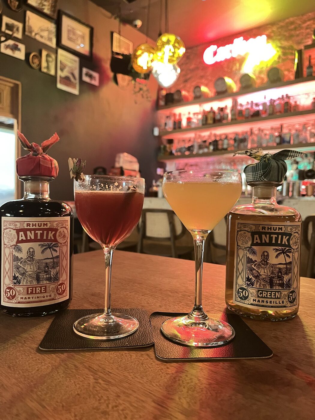 Deux cocktails au Caribou, à Marseille, servis à côté des bouteilles ANTIK Fire et Green