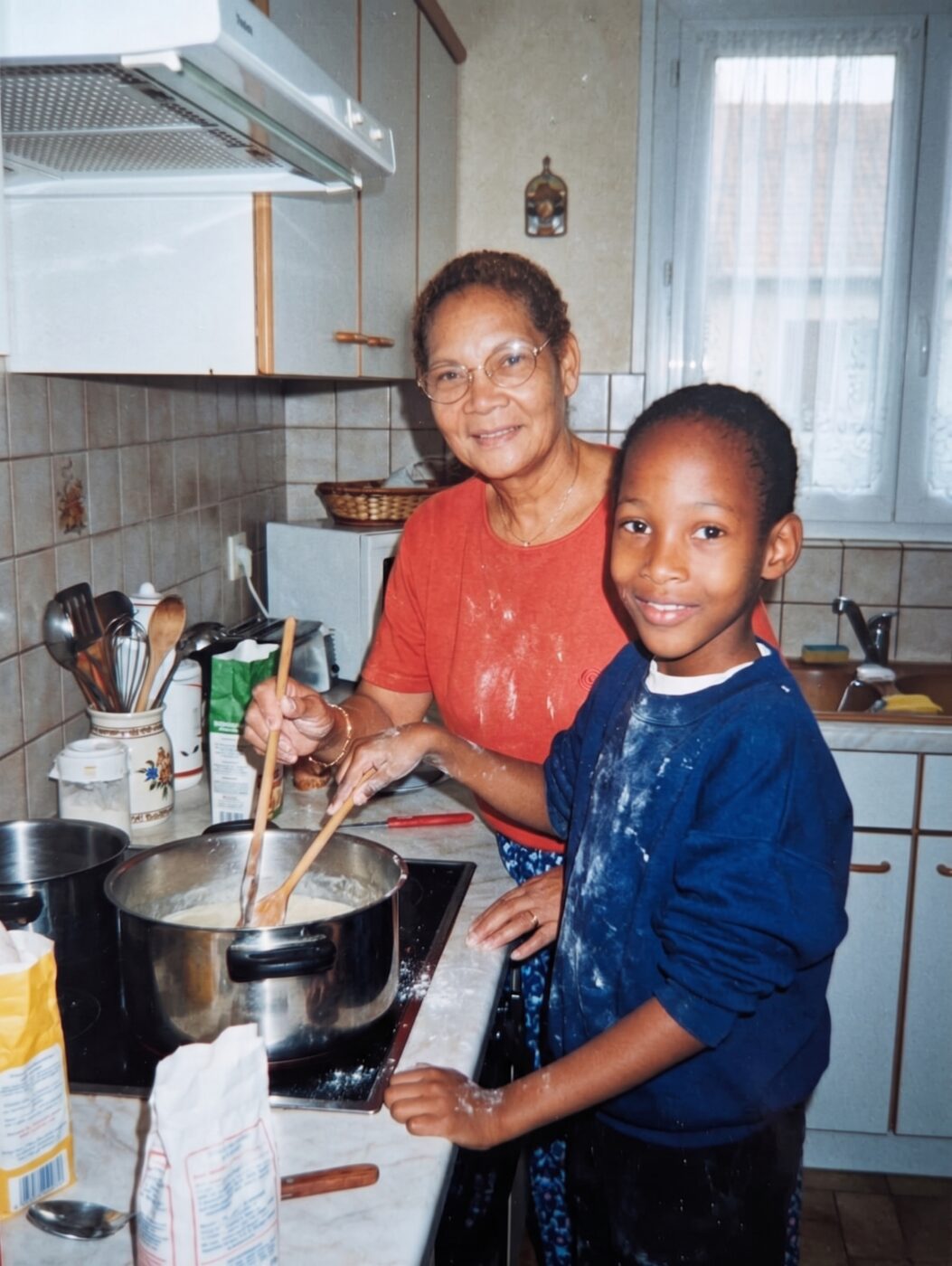 Maminus et Marvin enfant dans sa cuisine en Martinique, devant une casserole